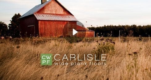 Red barn in a grassy field under a blue sky with Carlisle branding.
