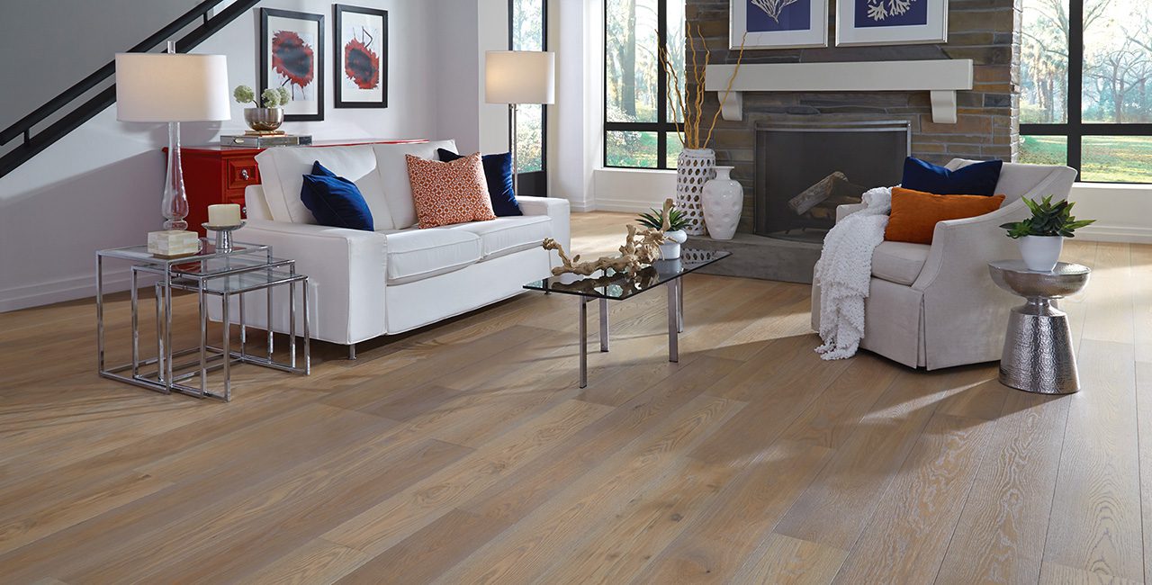 Bright living room with a white sofa, glass table, and wide plank flooring.