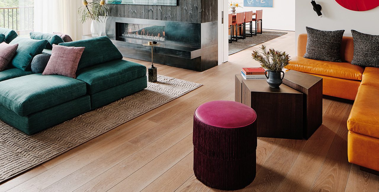 Modern living room with dark green sofa and wide plank flooring for a warm, inviting atmosphere.