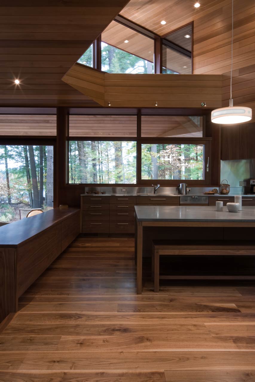 Modern kitchen with large windows and clean lines, featuring wide plank flooring.