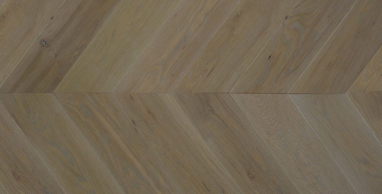 Herringbone wide plank flooring with varied texture and brown tones.