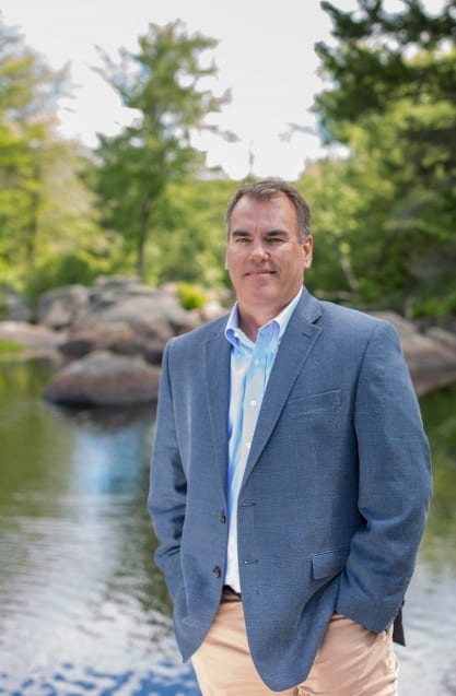 Man beside stream near forest Man standing outdoord near water