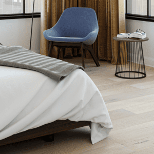 Cozy bedroom with wide plank flooring and a gray-striped blanket on the bed.