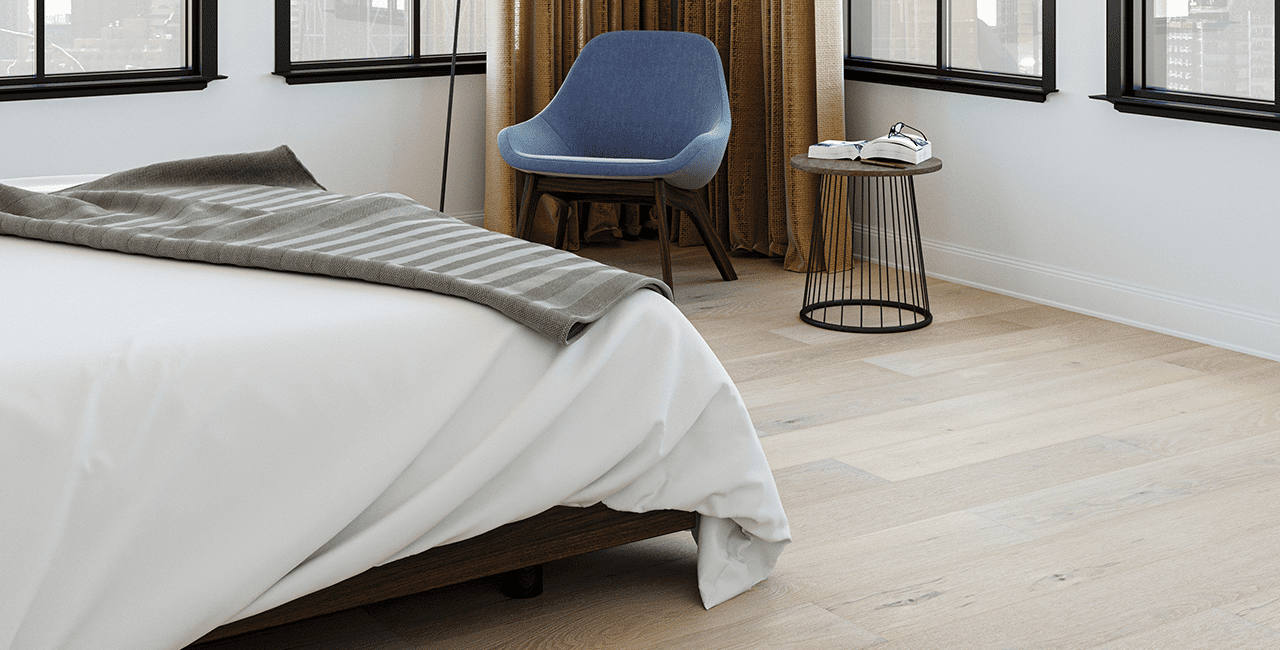 Cozy bedroom with wide plank flooring and a gray-striped blanket on the bed.