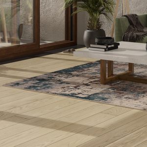 Modern living room with table and green sofa on wide plank floor.