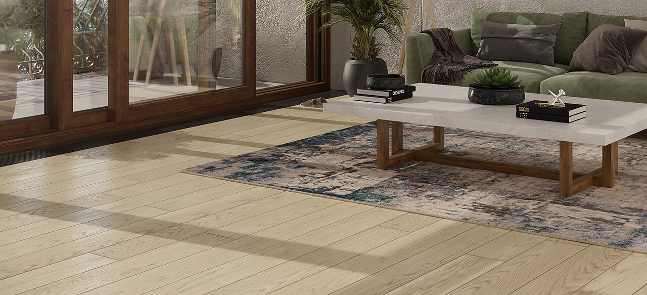 Modern living room with table and green sofa on wide plank floor.