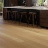 Kitchen with stools along marble island and wide plank flooring.