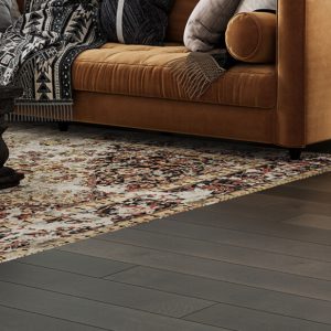 Leather sofa with pillows on dark wide plank flooring in cozy living room.