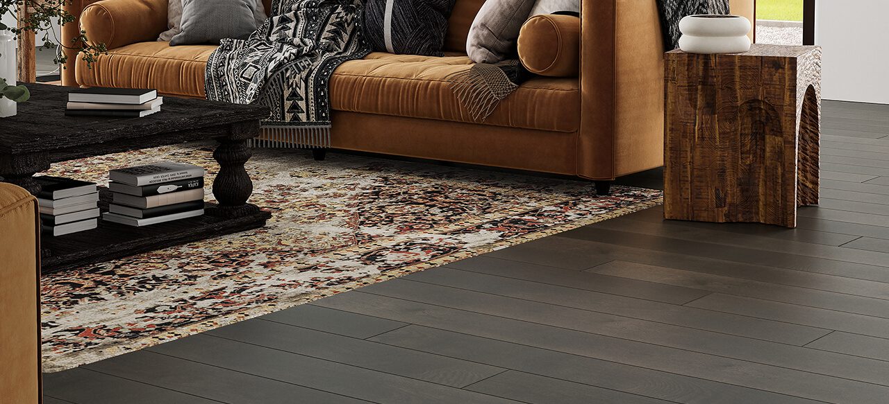 Leather sofa with pillows on dark wide plank flooring in cozy living room.