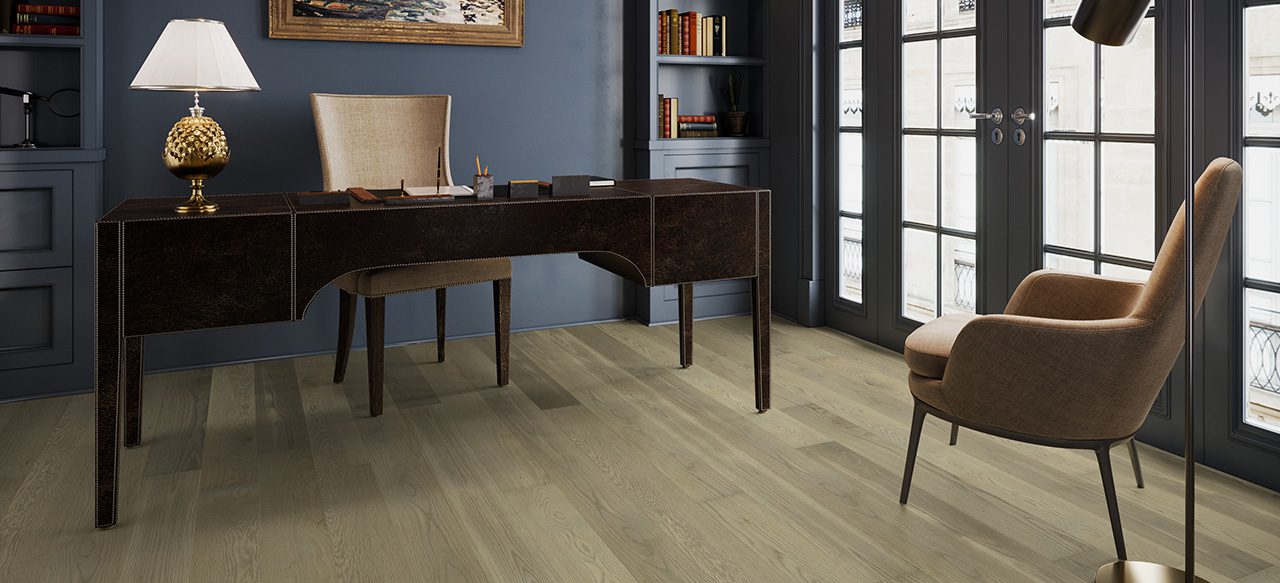 Dark desk in elegant study with wide plank wood flooring.