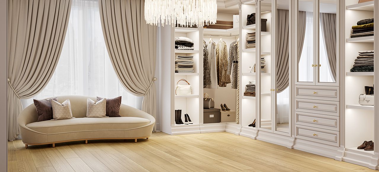 Luxurious walk-in closet with beige sofa, chandelier, and wide plank wooden flooring.