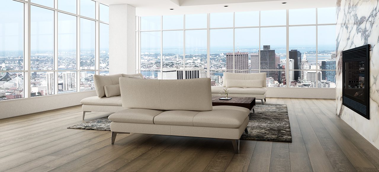 Modern high-rise apartment with beige couch, fireplace, and wide plank flooring overlooking a cityscape.