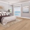 Spacious bedroom with wide plank floor, plush bedding, ocean view.