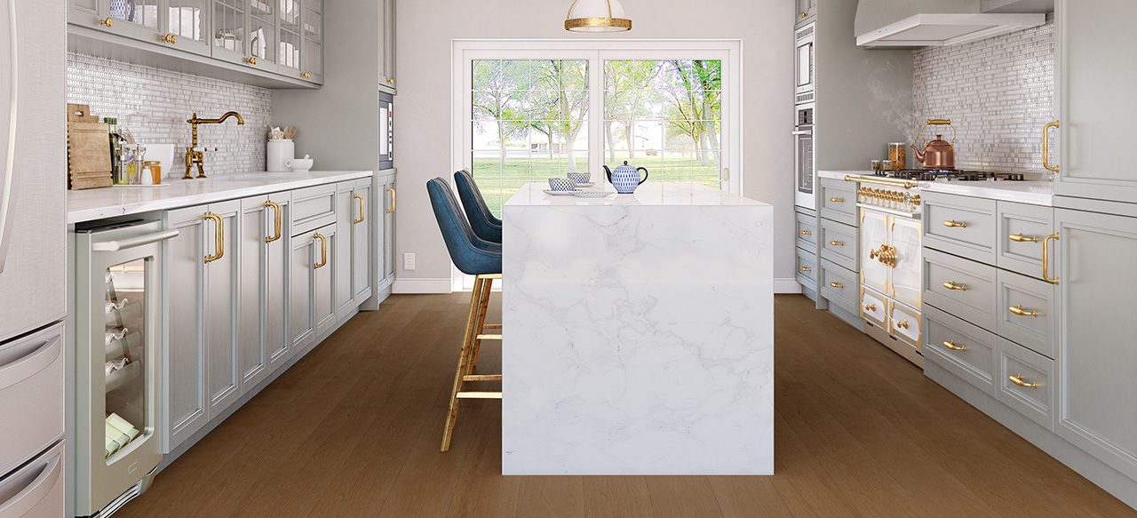 White marble island in modern kitchen with wide plank flooring and blue chairs.