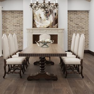 Wooden dining table on wide plank floor, surrounded by ornate chairs.