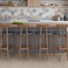 Wooden high table with chairs, wide plank flooring, hexagonal tile backsplash.