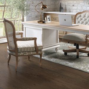 Wooden desk with laptop in an office with wide plank flooring.